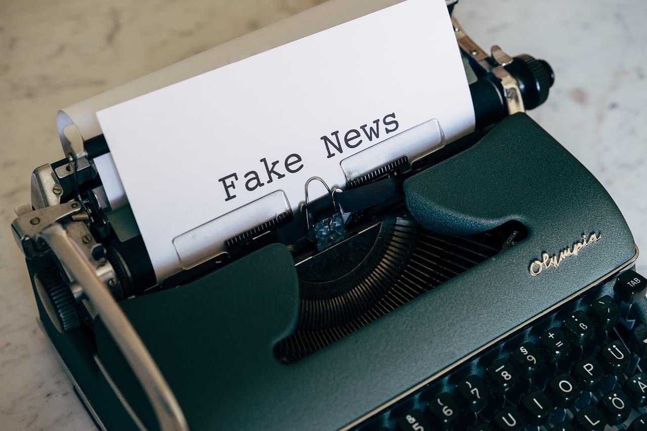 Alte Schreibmaschine mit einem eingespannten Blatt Papier, auf dem „Fake News“ steht